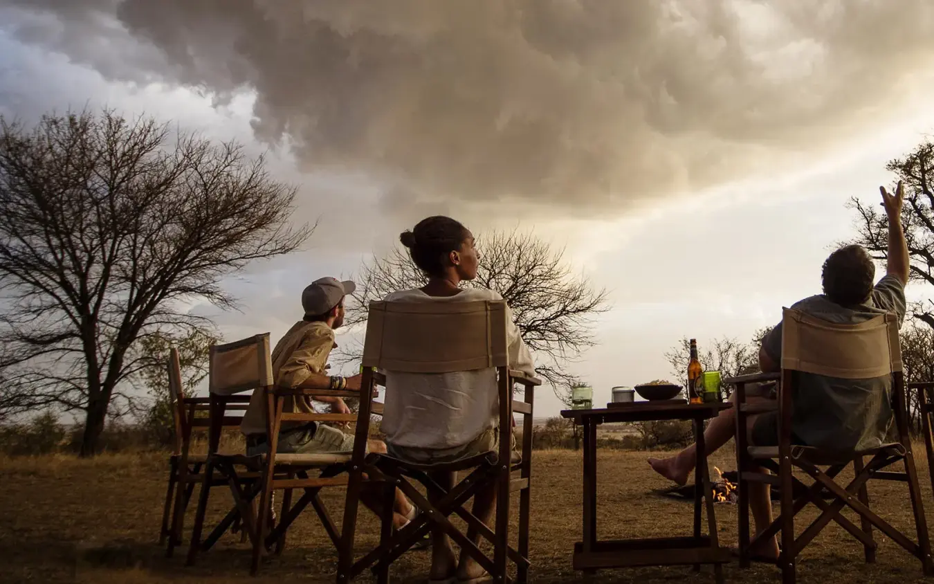 Guests relaxing in chairs overlooking savanna landscape, Serian Serengeti Lamai, Serengeti National Park, Tanzania