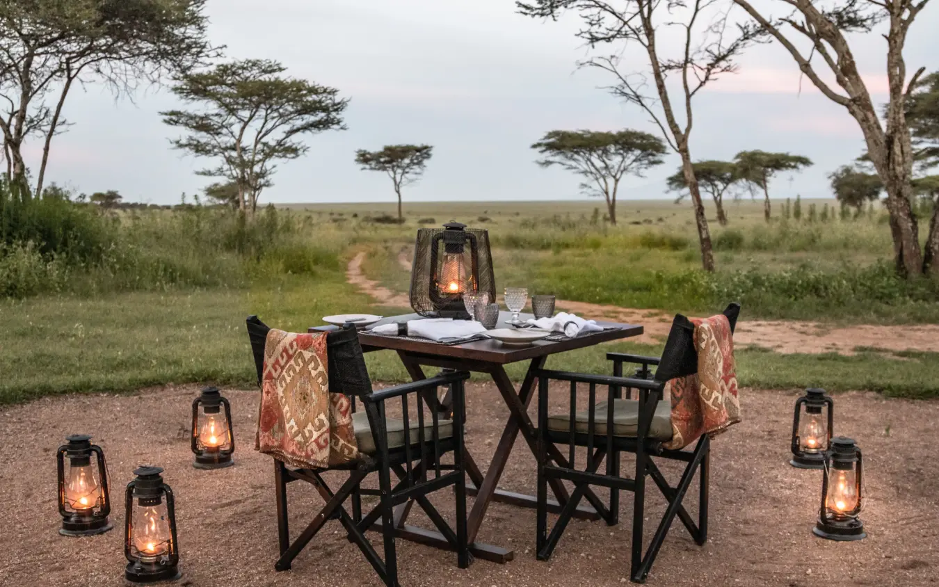 outdoor dining setup with lanterns in African savanna, Nyasi Tented Camp, Serengeti National Park, Tanzania