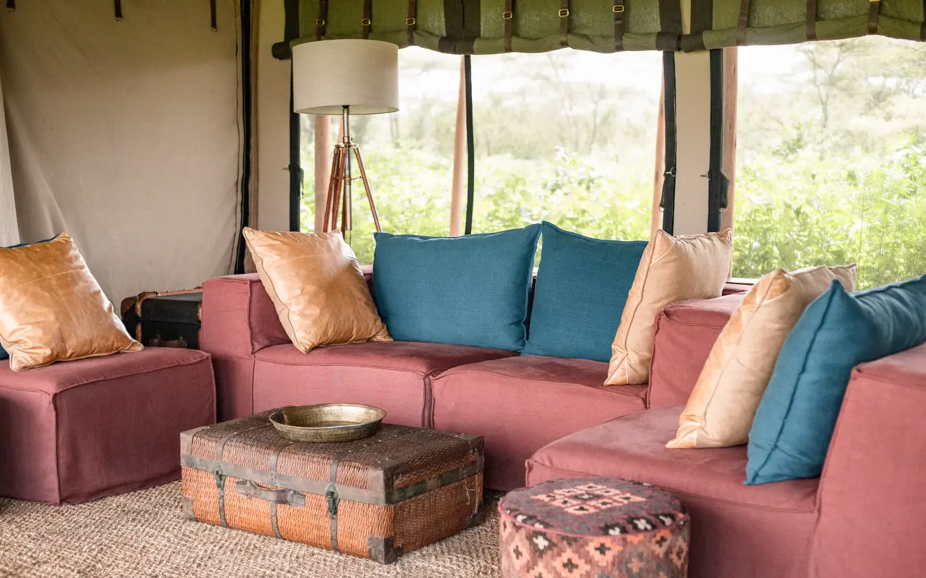 Family tent interior with pink seating and blue cushions, Nyasi Tented Camp, Serengeti National Park, Tanzania