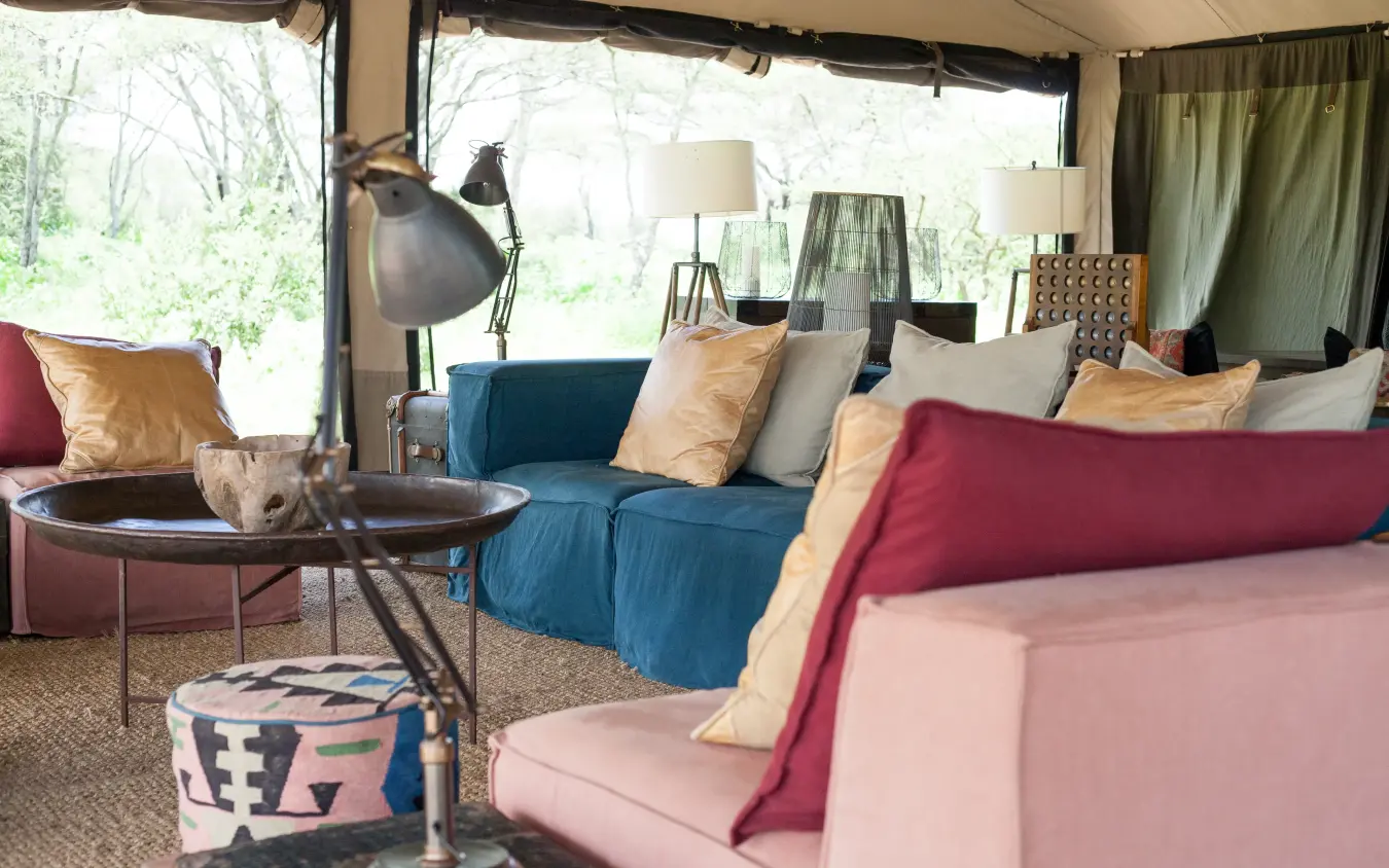 Open-air lounge with colorful seating and large windows overlooking nature, Nyasi Tented Camp, Serengeti National Park, Tanzania