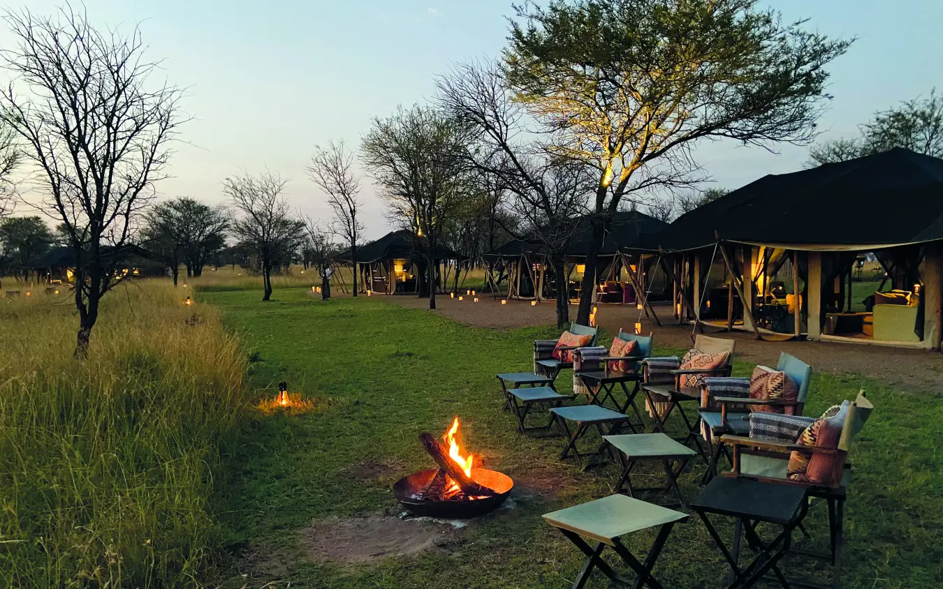Evening campfire gathering with seating and safari tents, Nyasi Tented Camp, Serengeti National Park, Tanzania