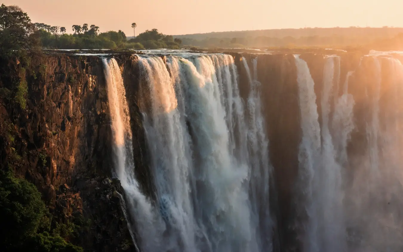 Massive waterfall cascading over rocky cliffs at sunrise