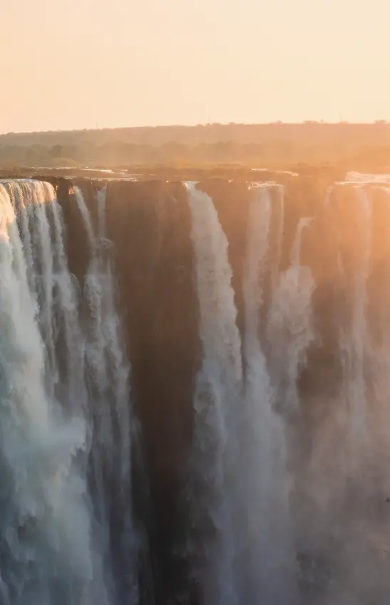 Massive waterfall cascading over rocky cliffs at sunrise