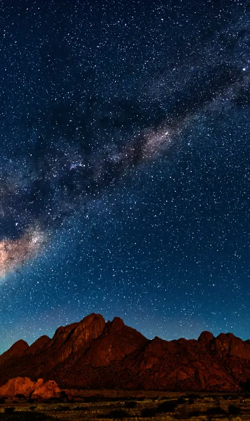 Rocky desert mountains silhouetted under starry night sky