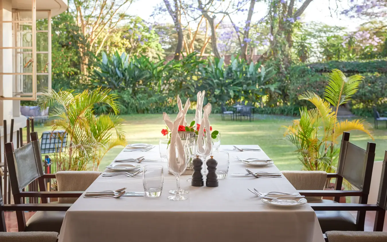 Elegant outdoor dining table with garden and lawn views, Legendary Lodge, Arusha, Tanzania