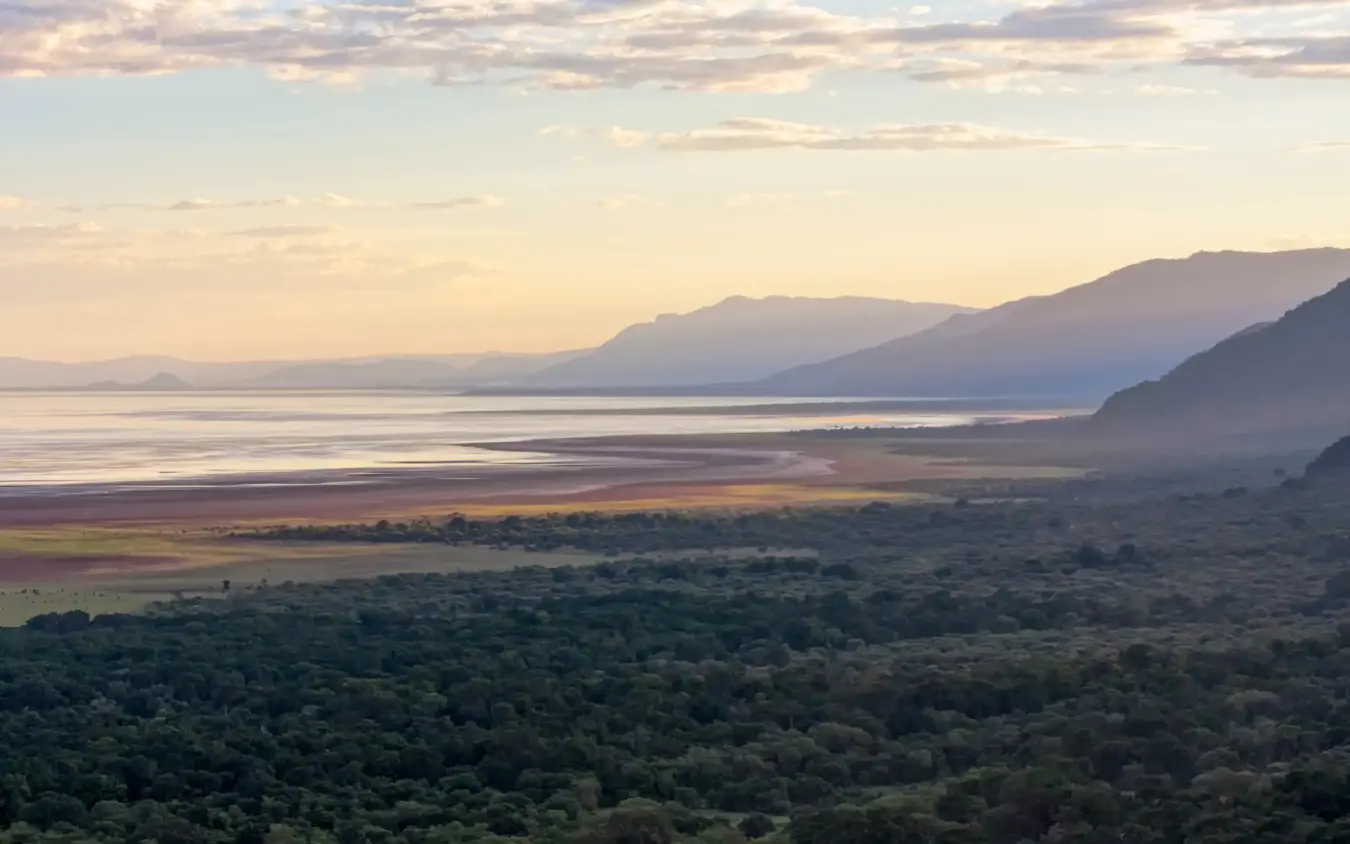 Dawn light over forested valley with distant mountains and lake, Legendary Lodge, Arusha, Tanzania