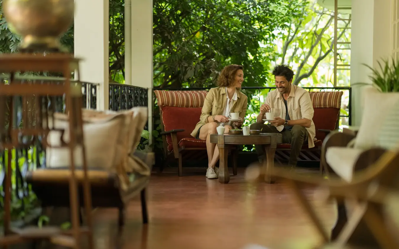 Two guests conversing in covered lounge area with garden views, Legendary Lodge, Arusha, Tanzania