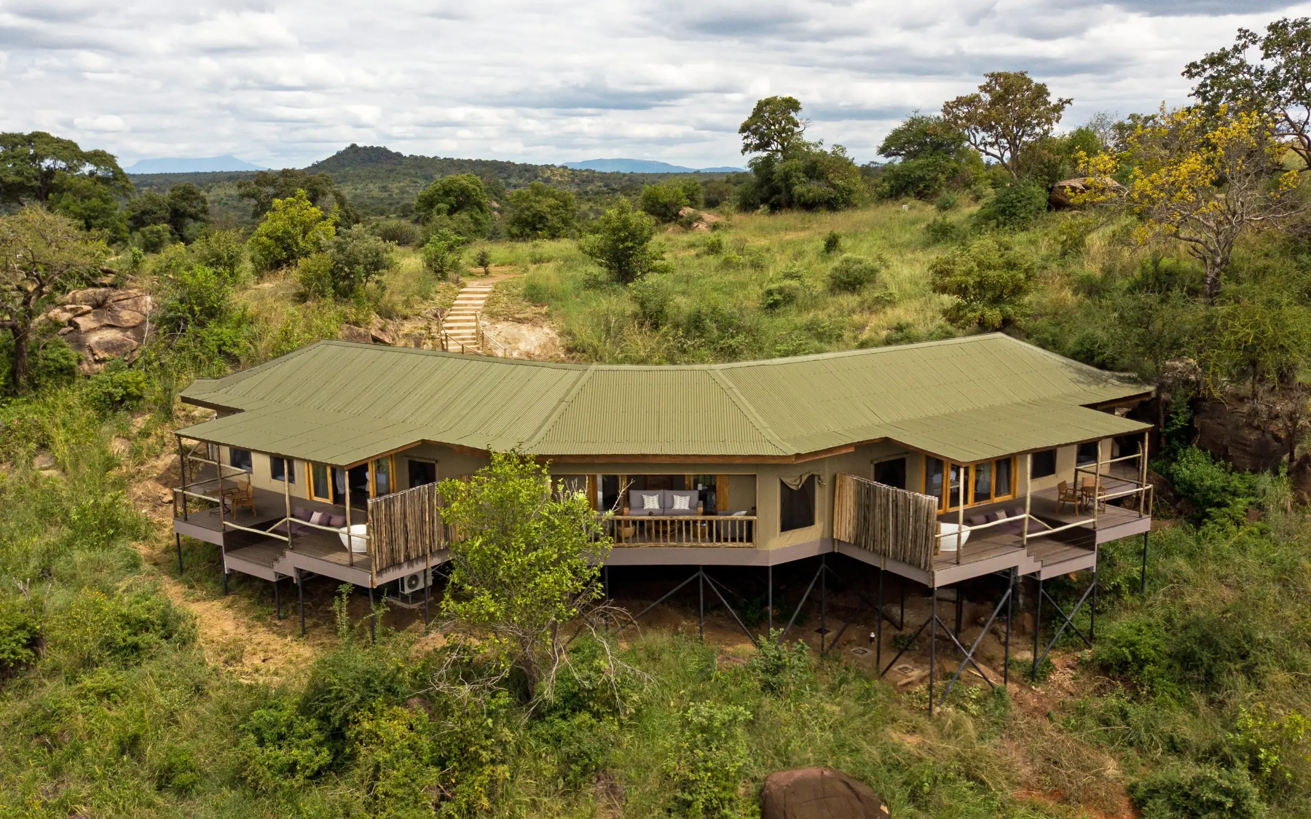 Elevated safari lodge with green metal roof nestled in woodland savanna, Mpingo Ridge Lodge, Tarangire National Park, Tanzania