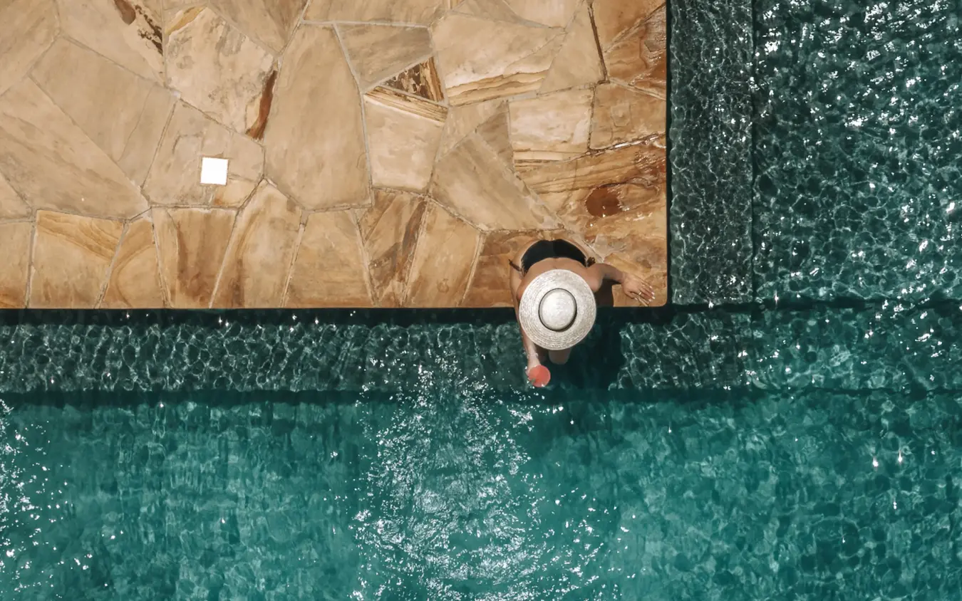 Person in hat at edge of pool overlooking tiled deck, Mpingo Ridge Lodge, Tarangire National Park, Tanzania