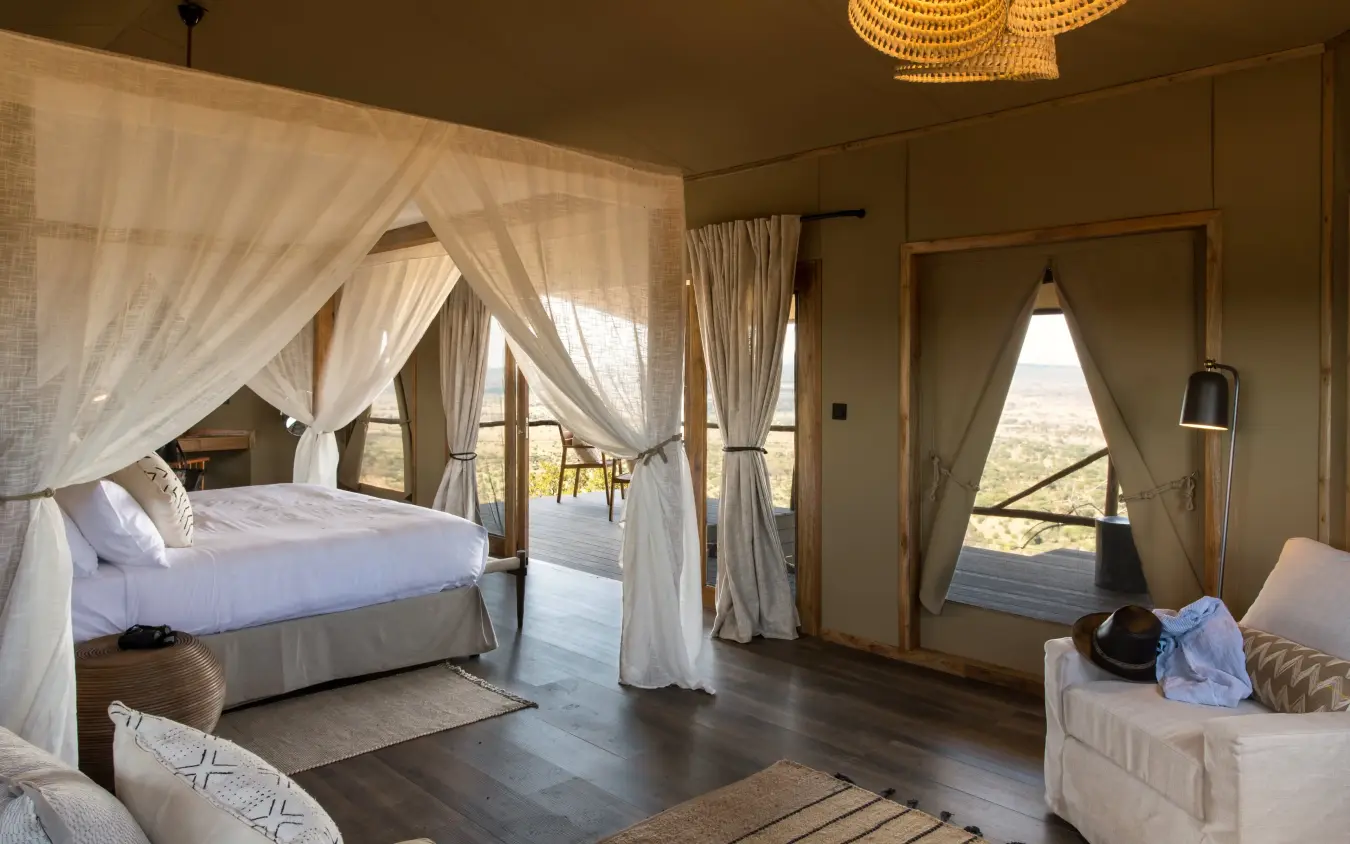 Luxury safari suite with canopy bed and savanna views through open doors, Mpingo Ridge Lodge, Tarangire National Park, Tanzania