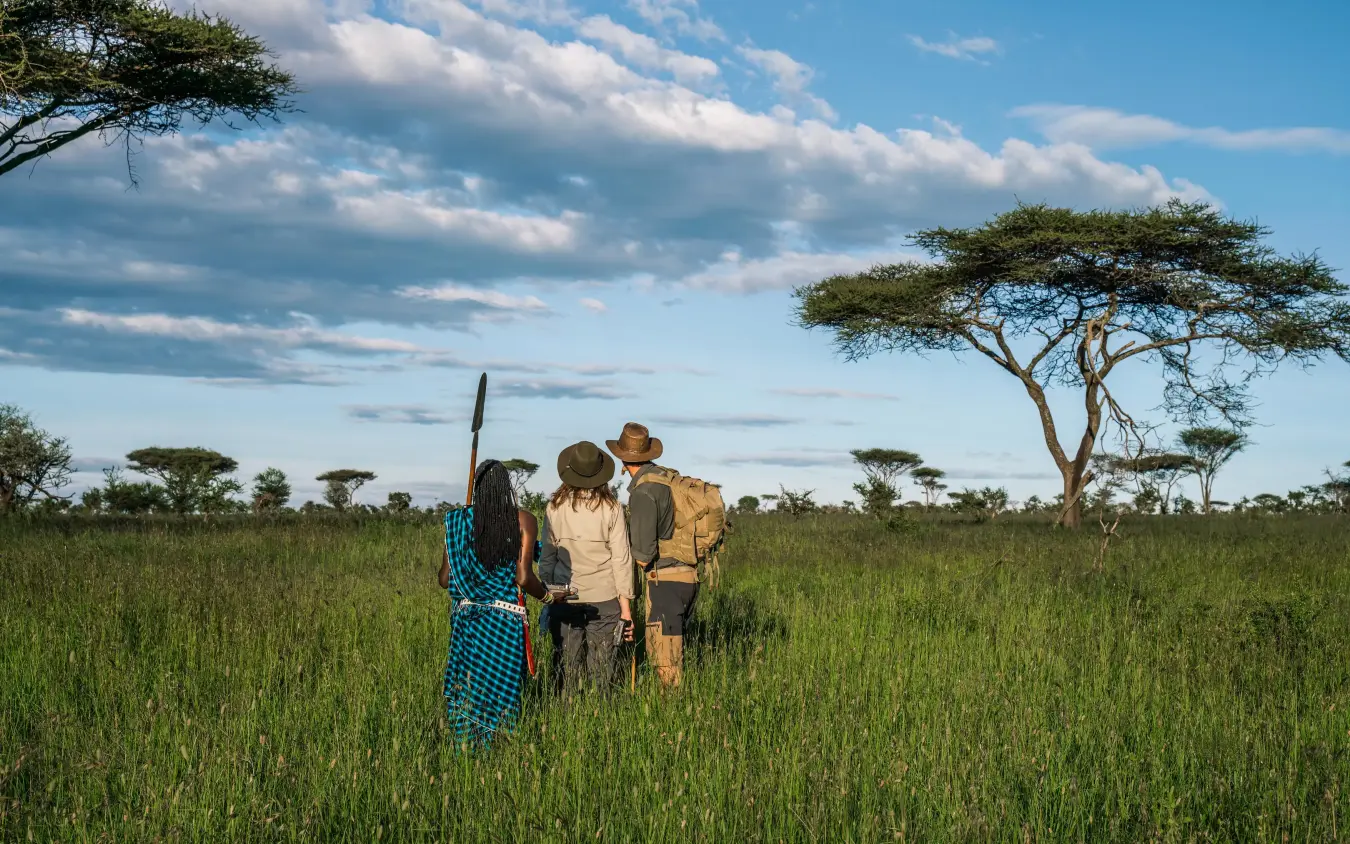 Guides and guests gathered in expansive grassland savanna, Lemala Ngorongoro, Ngorongoro Crater, Tanzania