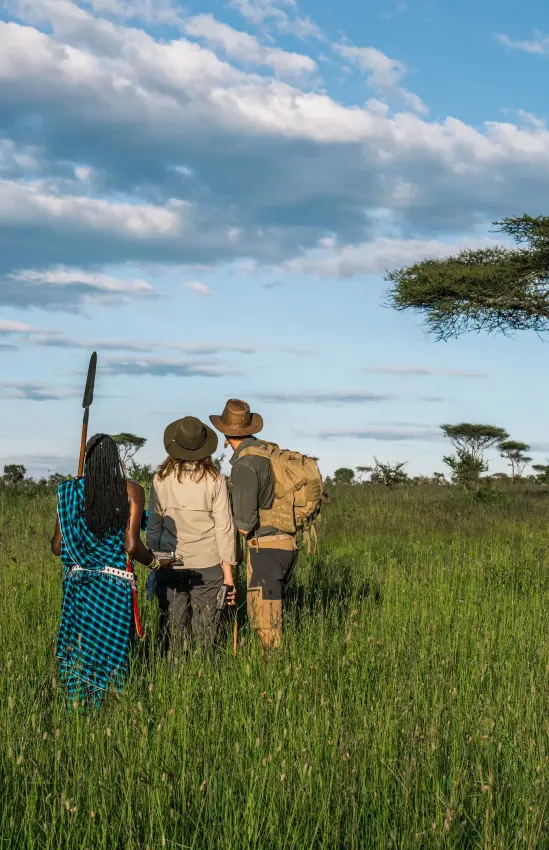 Guides and guests gathered in expansive grassland savanna, Lemala Ngorongoro, Ngorongoro Crater, Tanzania