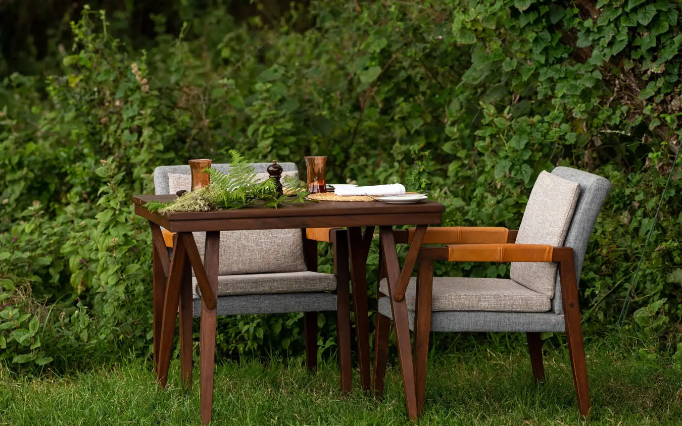 Wooden dining table and chairs set in garden, Lemala Ngorongoro, Ngorongoro Crater, Tanzania