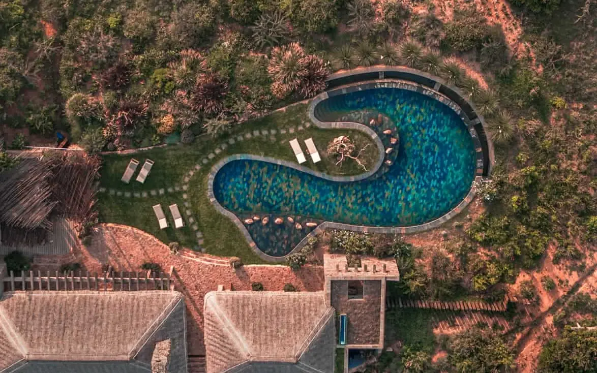 Curved swimming pool surrounded by manicured grounds and forest, Lengishu House, Laikipia Highlands, Kenya