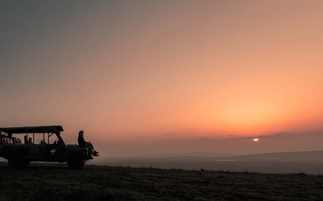 Safari vehicle silhouetted against dramatic sunset sky, Lengishu House, Laikipia Highlands, Kenya