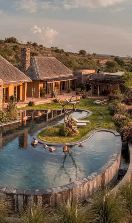 Curved swimming pool with guests surrounded by savanna landscape, Lengishu House, Laikipia Highlands, Kenya