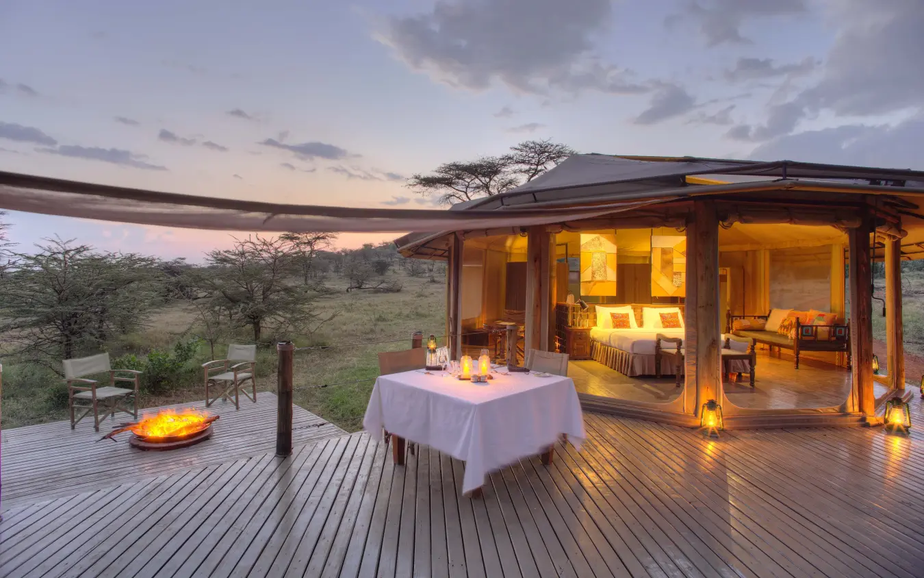 Sunset dinner setup on lodge deck overlooking African savanna landscape, Leopard Hill, Maasai Mara, Kenya