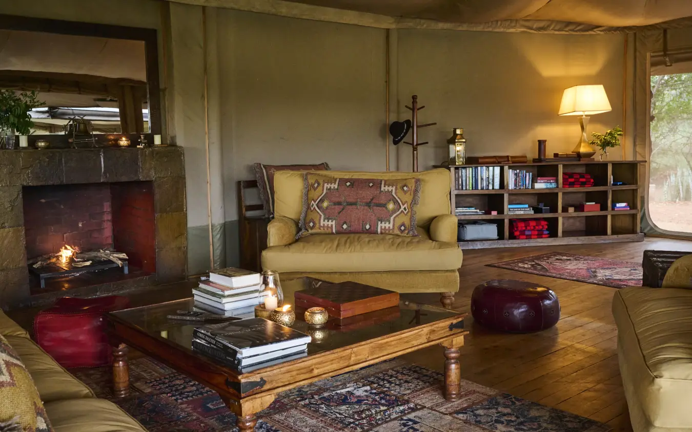 Luxury safari lodge interior with fireplace, seating area and canvas walls, Leopard Hill, Maasai Mara, Kenya