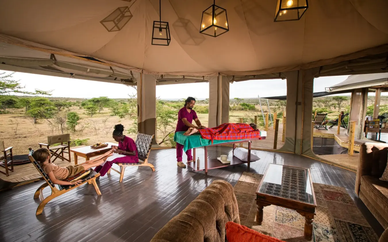 Safari lodge interior with guests and red blankets overlooking savanna landscape, Leopard Hill, Maasai Mara, Kenya