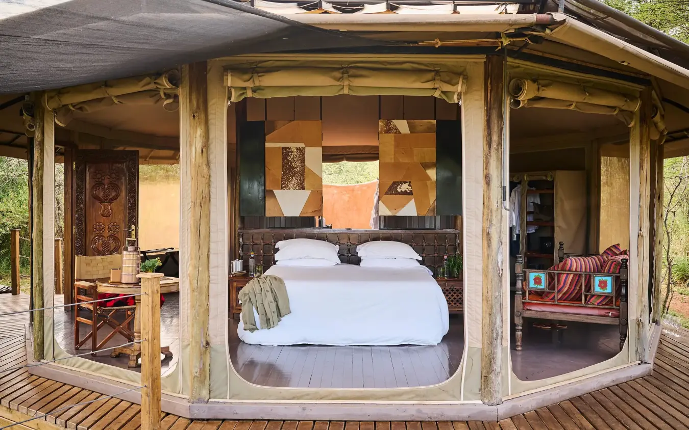 Luxury safari tent bedroom with open canvas walls and wooden deck, Leopard Hill, Maasai Mara, Kenya