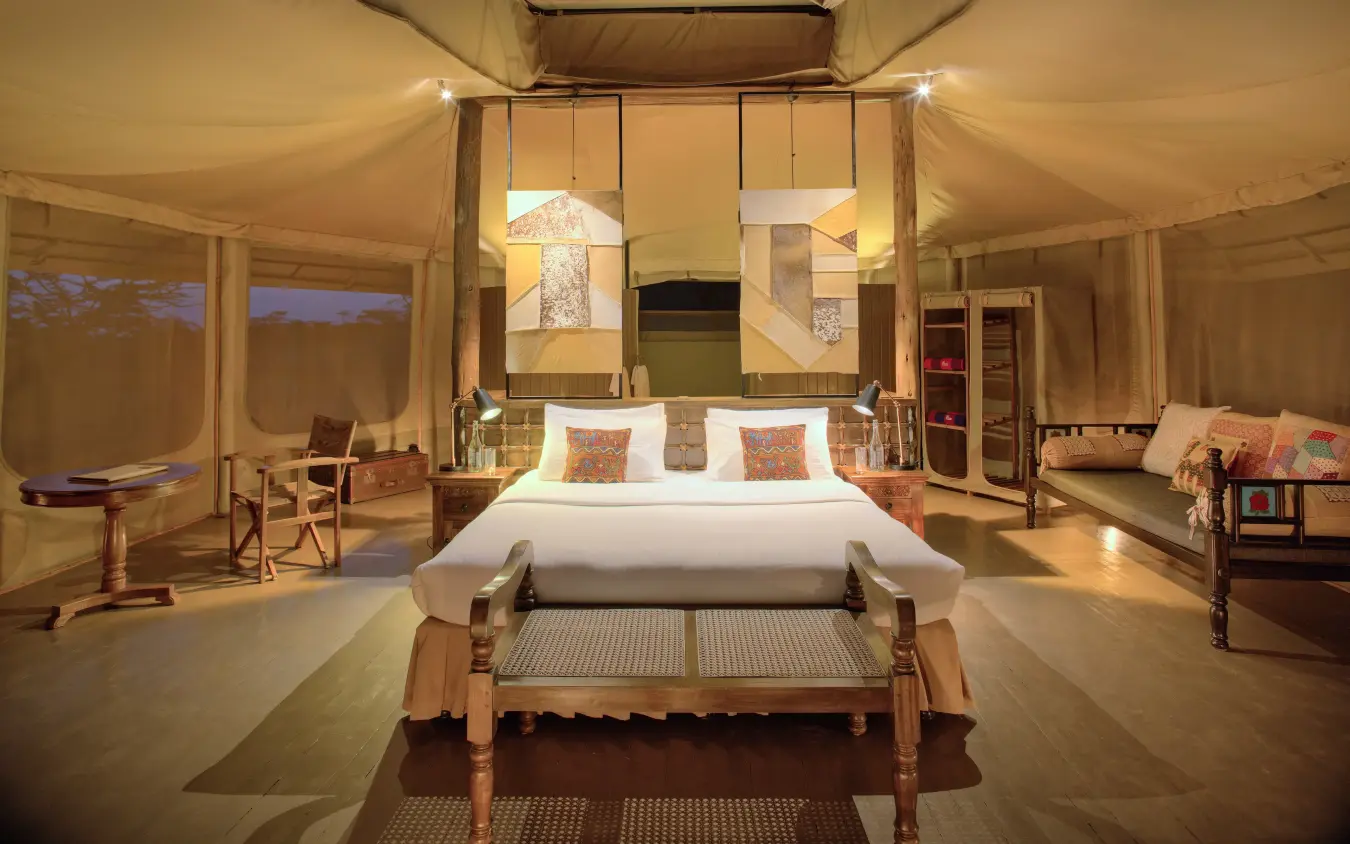 Luxury canvas tent bedroom interior with ambient lighting at dusk, Leopard Hill, Maasai Mara, Kenya
