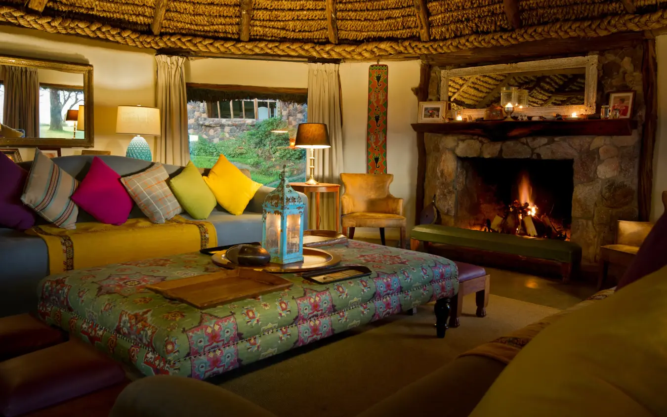 Luxurious lounge with fireplace, colorful cushions, thatched ceiling, Lewa House, Laikipia Highlands, Kenya