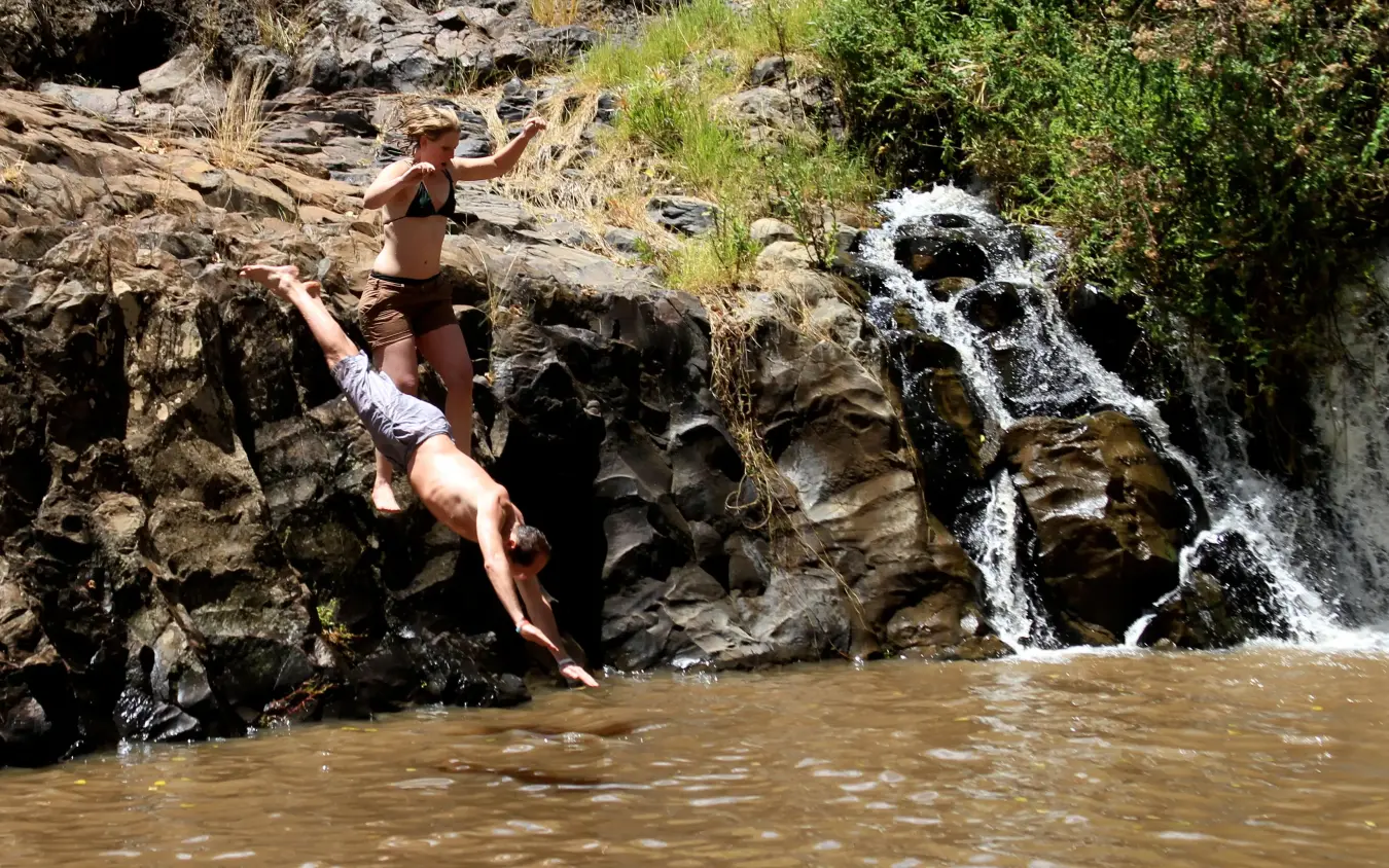 Guest cliff jumping into river near waterfall, Lewa Wilderness, Laikipia Highlands, Kenya