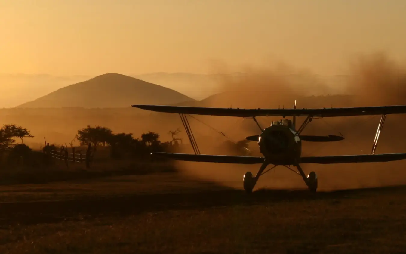 Small aircraft landing on dusty airstrip at sunrise, Lewa Wilderness, Laikipia Highlands, Kenya