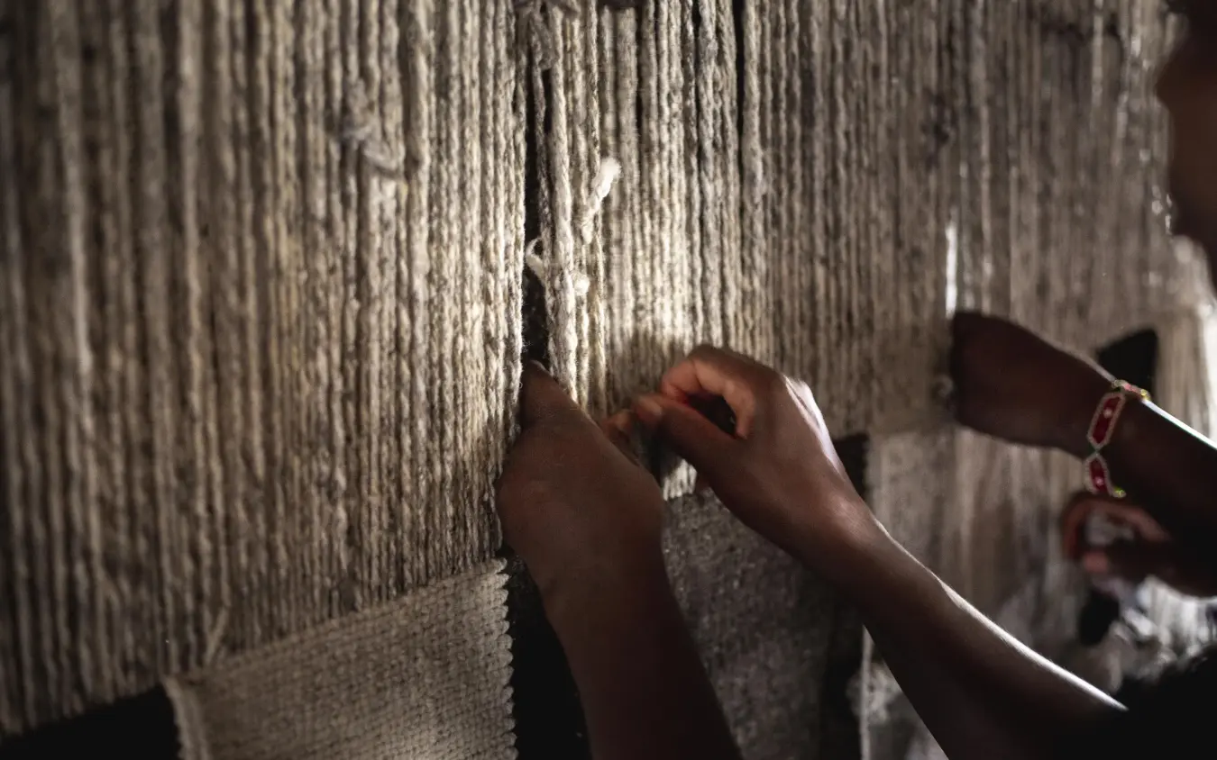 Hands touching woven textile wall hanging closely, Lewa Wilderness, Laikipia Highlands, Kenya