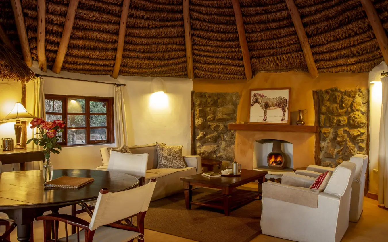 Warmly lit lounge with thatched ceiling and fireplace, Lewa Wilderness, Laikipia Highlands, Kenya