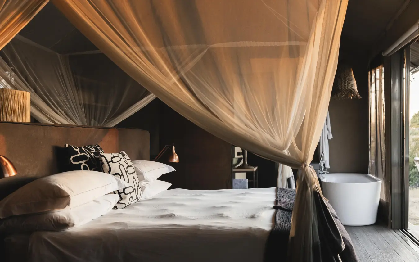 Luxury bedroom with sheer canopy drapes and en-suite bathroom, Linkwasha Camp, Hwange National Park, Zimbabwe