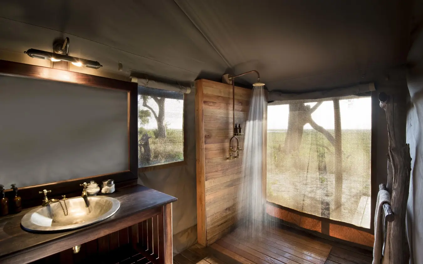 Open-air bathroom with wooden finishes and landscape views, Linyanti Bush Camp, Linyanti Wildlife Reserve, Botswana