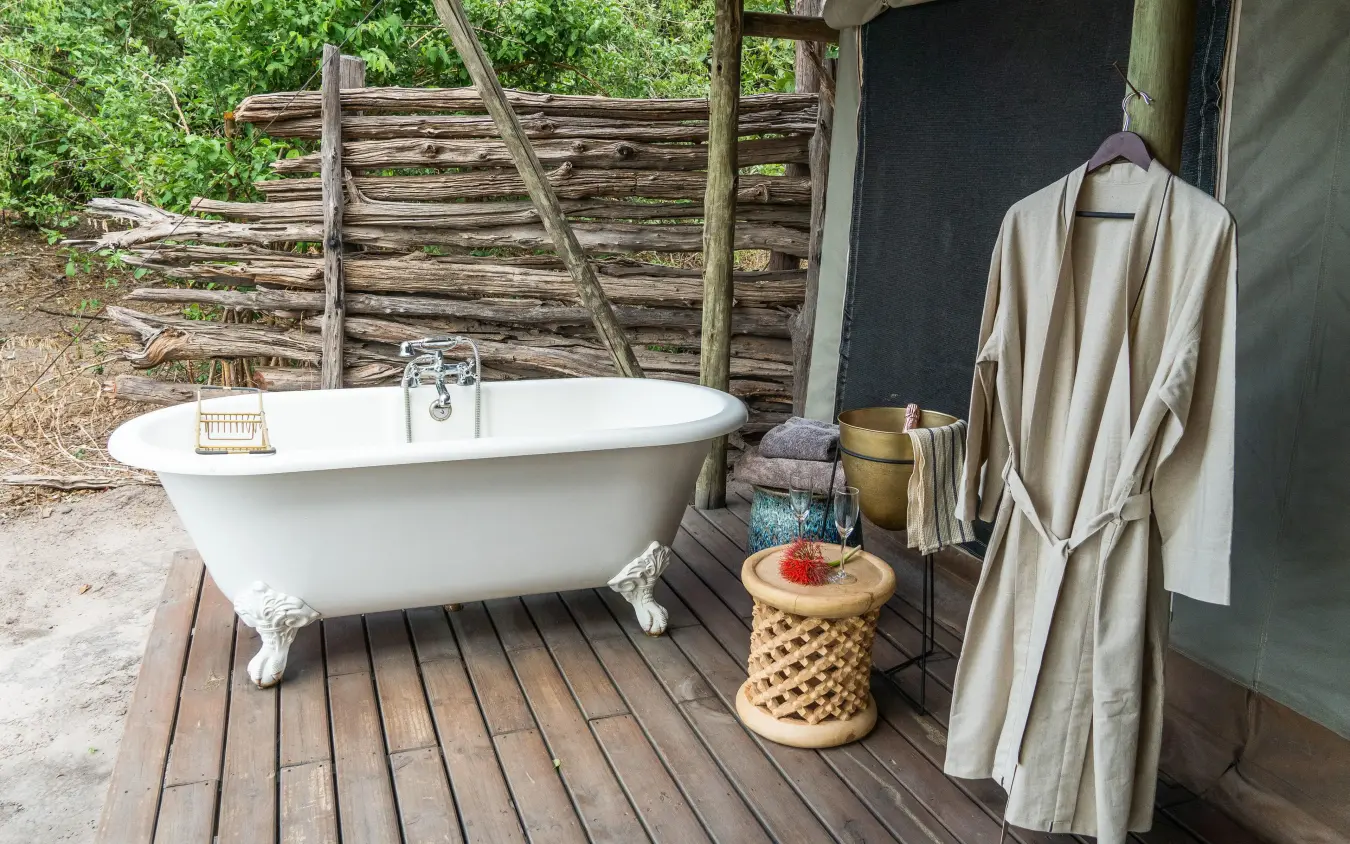Outdoor bathtub on wooden deck with natural surroundings, Linyanti Bush Camp, Linyanti Wildlife Reserve, Botswana