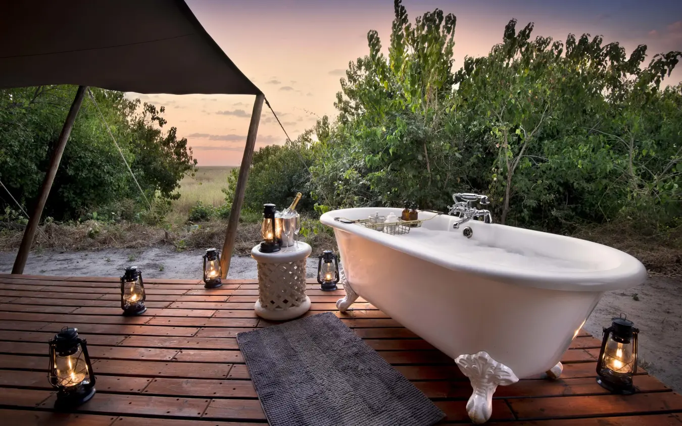 Freestanding bathtub on wooden deck at sunset, Linyanti Bush Camp, Linyanti Wildlife Reserve, Botswana