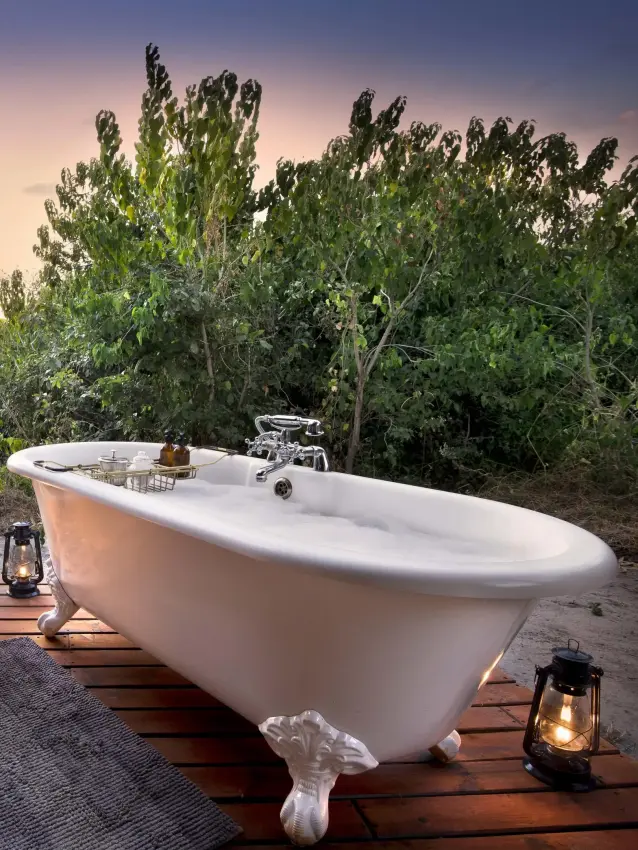 Freestanding bathtub on wooden deck at sunset, Linyanti Bush Camp, Linyanti Wildlife Reserve, Botswana