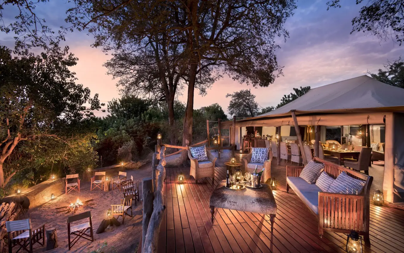 Wooden deck with seating areas overlooking savanna at dusk, Linyanti Bush Camp, Linyanti Wildlife Reserve, Botswana