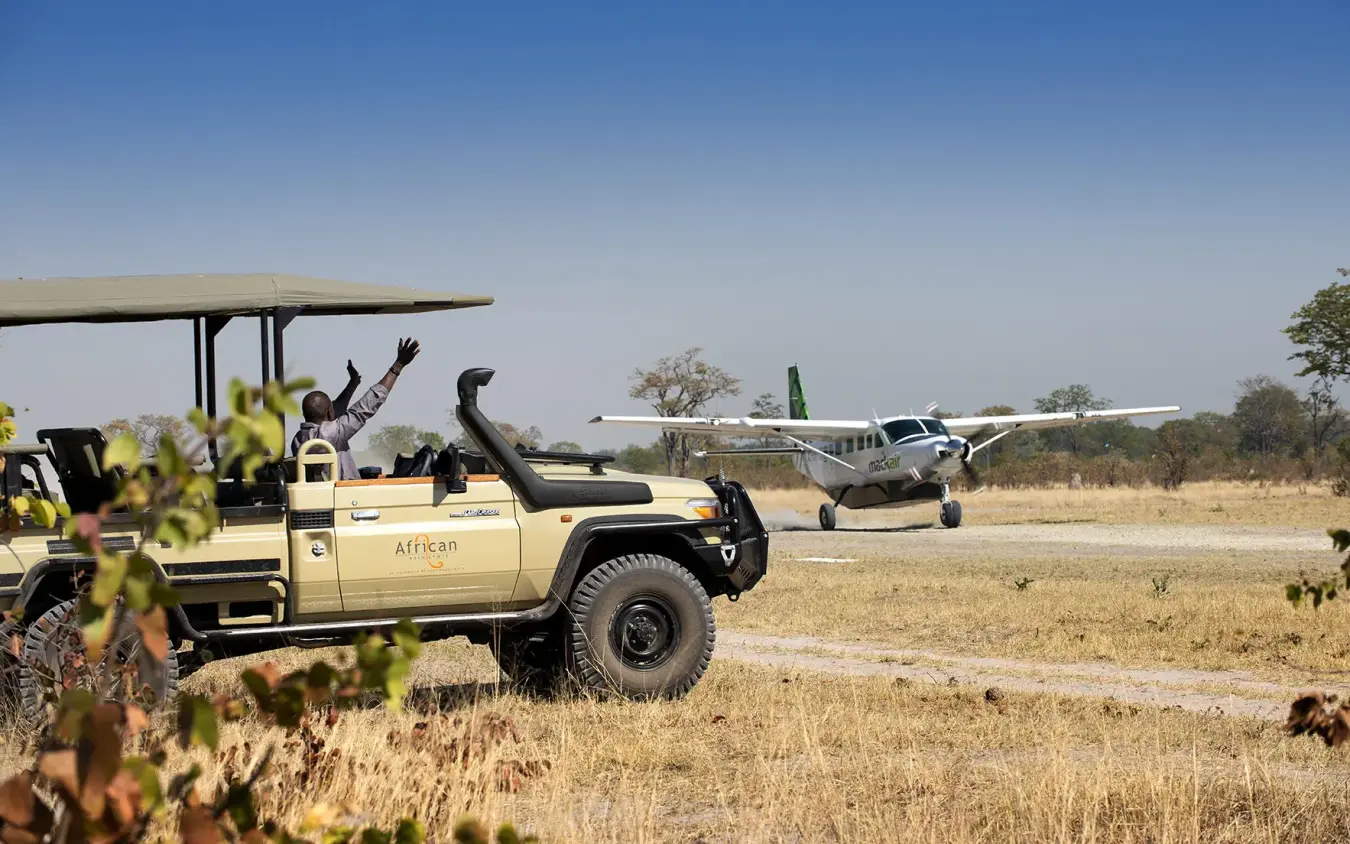 Safari vehicle with guests on airstrip at bush camp, Linyanti Bush Camp, Linyanti Wildlife Reserve, Botswana