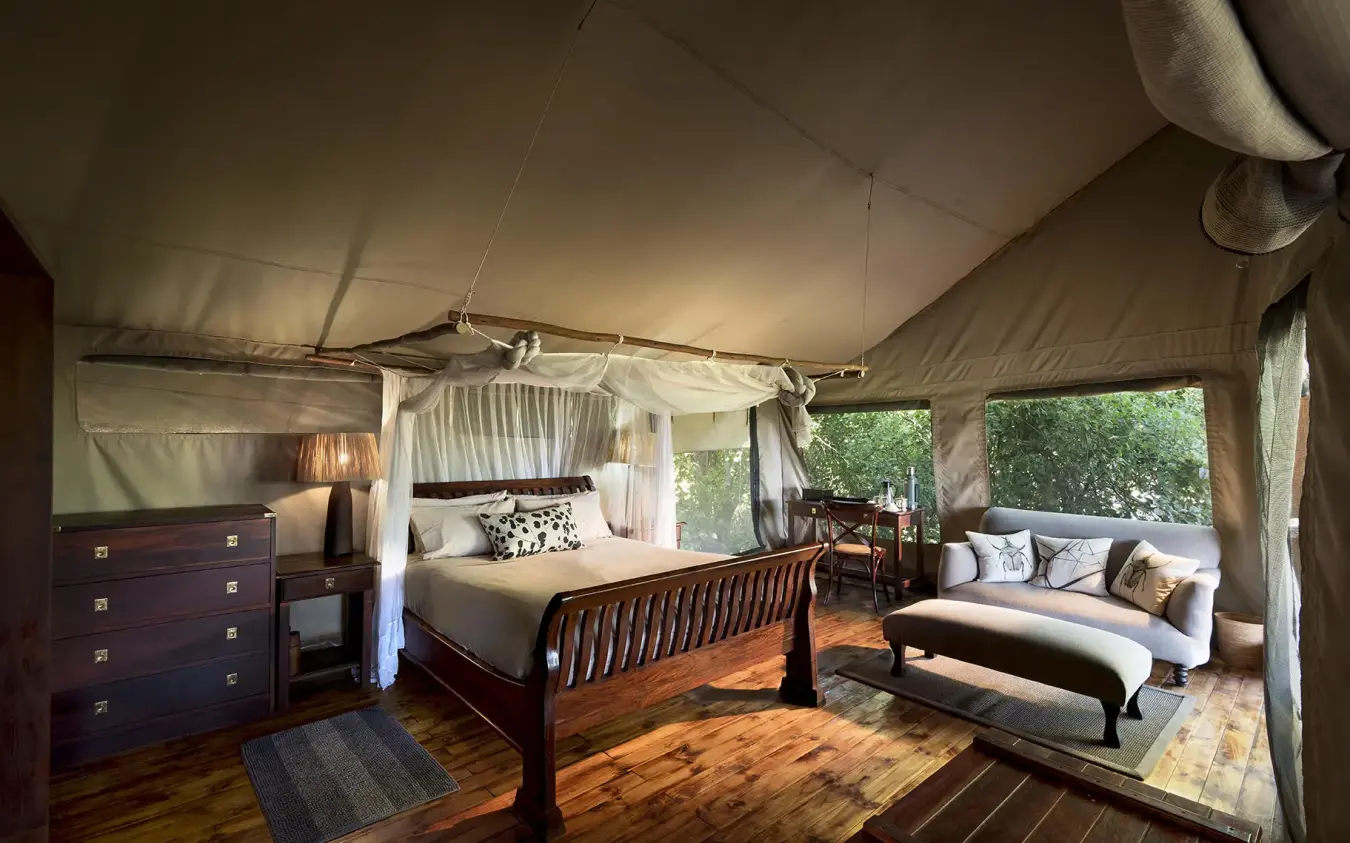 Luxury safari tent bedroom with four-poster bed and seating area, Linyanti Bush Camp, Linyanti Wildlife Reserve, Botswana