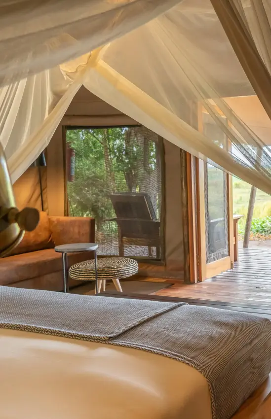 Safari tent bedroom with canopy bed and landscape views, Linyanti Bush Camp, Linyanti Wildlife Reserve, Botswana