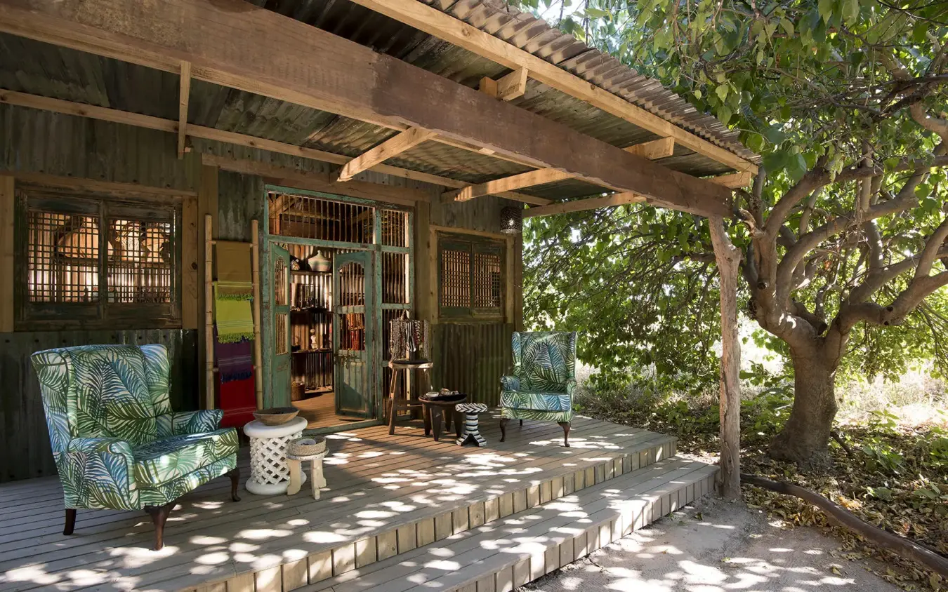 Covered outdoor lounge with seating under wooden pergola, Linyanti Bush Camp, Linyanti Wildlife Reserve, Botswana
