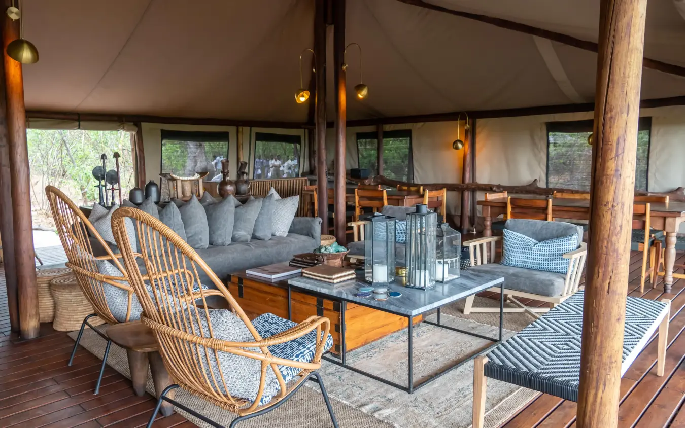 Canvas tent lounge with woven chairs and gray seating, Linyanti Bush Camp, Linyanti Wildlife Reserve, Botswana