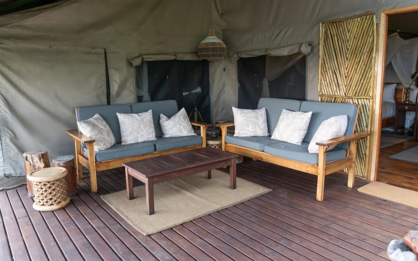 Canvas tent interior with wooden sofas and cushions, Linyanti Ebony, Linyanti Wildlife Reserve, Botswana
