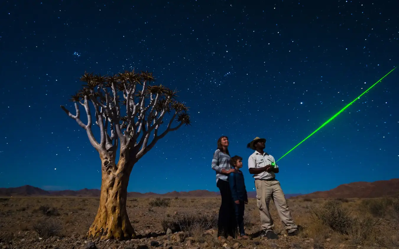 Guests with laser pointer at night under stars near quiver tree, Little Kulala, Sossusvlei, Namibia