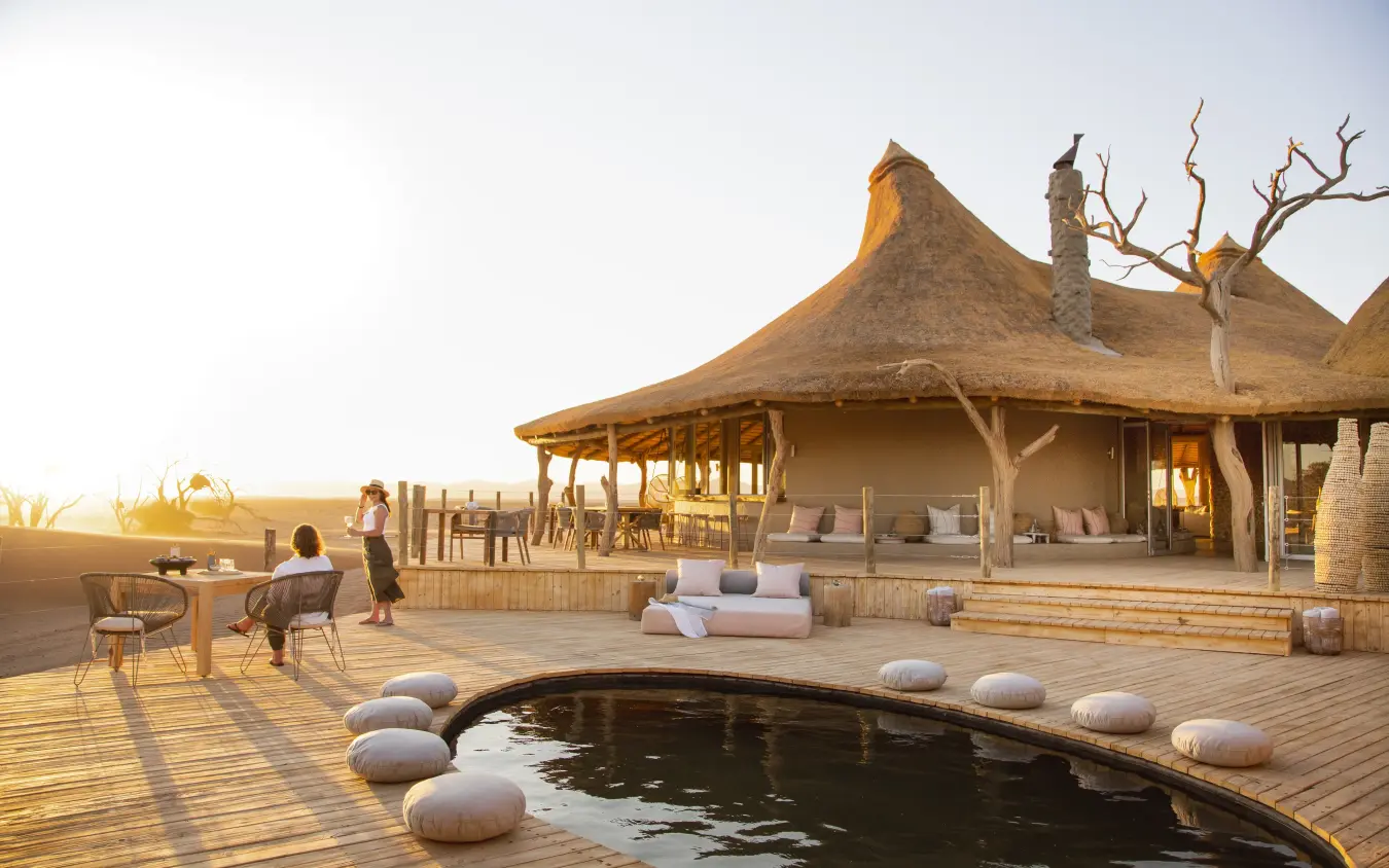 Thatched pavilion with infinity pool at sunset overlooking plains, Little Kulala, Sossusvlei, Namibia