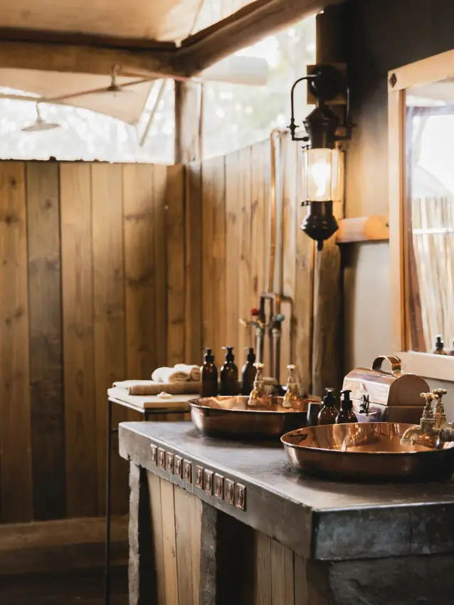 Luxurious bathroom with dual copper vessel sinks and wooden partition shower, Little Makalolo, Hwange National Park, Zimbabwe