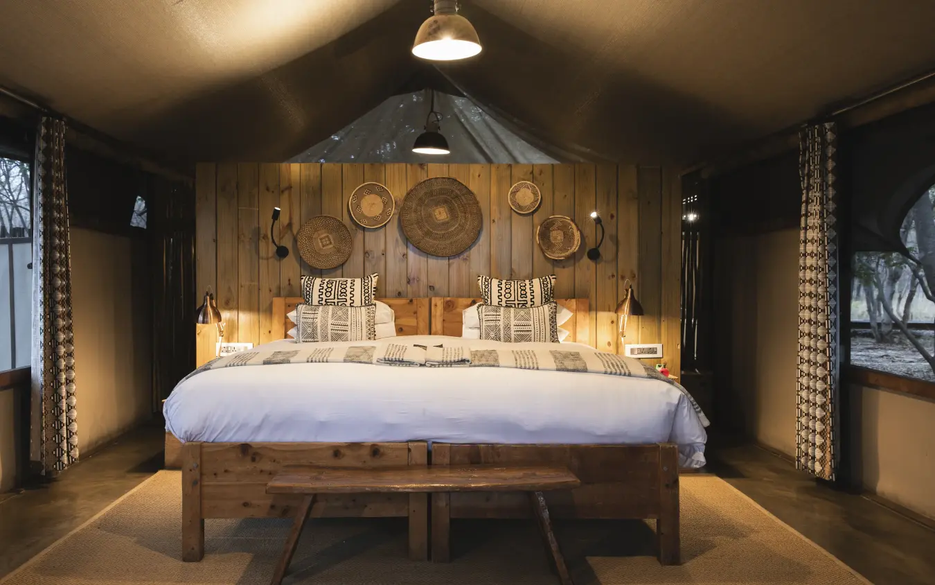 Luxury safari tent bedroom with woven basket wall decor and wooden furnishings, Little Makalolo, Hwange National Park, Zimbabwe