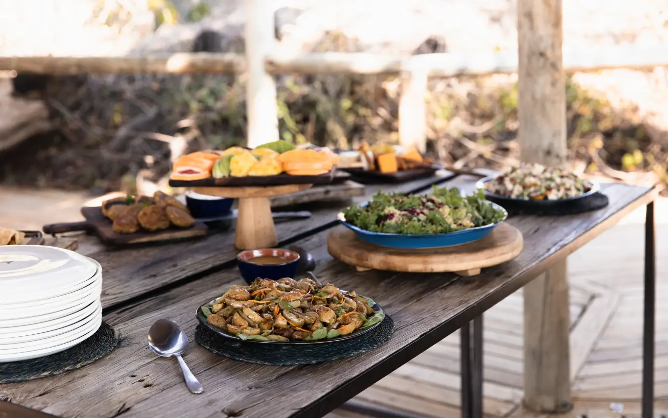 Outdoor dining table with plated dishes and ocean view, Little Vumbura, The Okavango Delta, Botswana