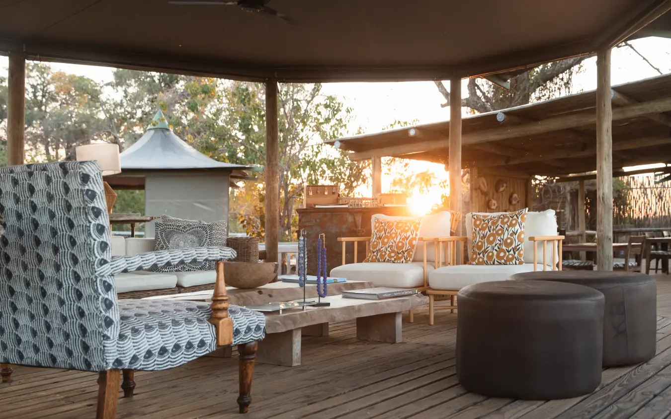 Covered outdoor lounge area with patterned seating and sunset views over bushland, Little Vumbura, The Okavango Delta, Botswana