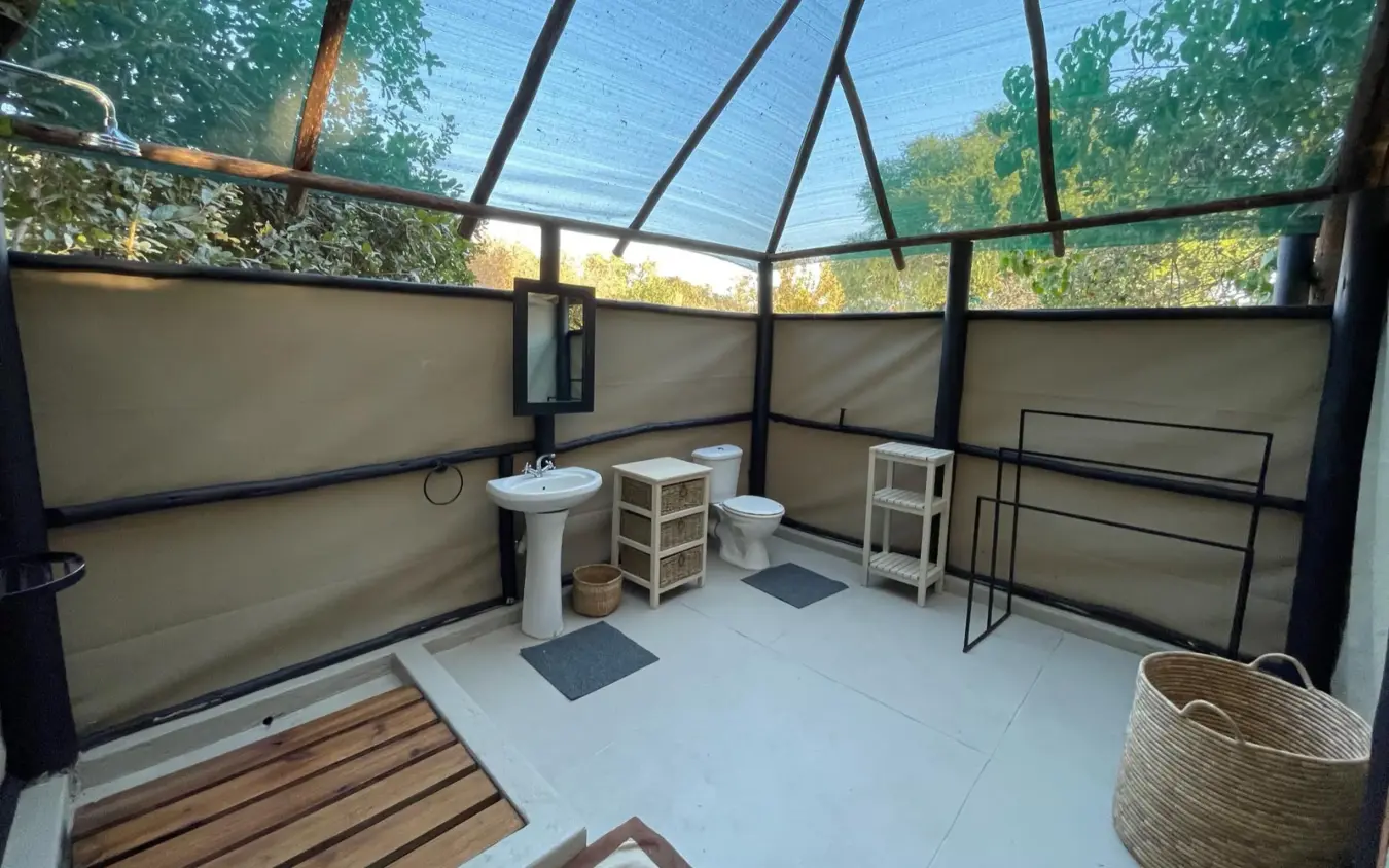 Outdoor bathroom with pedestal sink and toilet under mesh roof, Little Vundu, Mana Pools, Zimbabwe