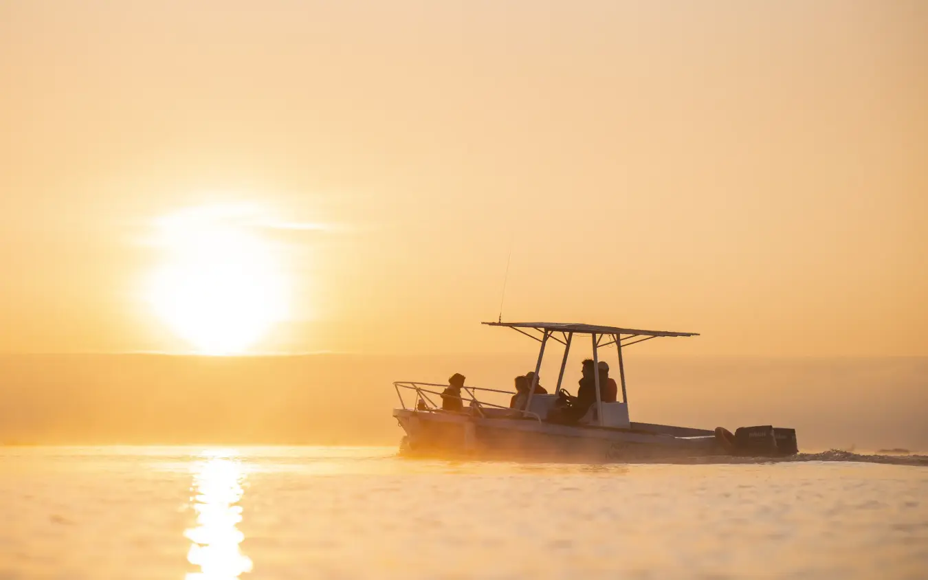 Fishing boat with passengers at sunrise over calm water, Loldia House, Rift Valley Lakes, Kenya